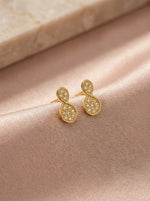 18k Gold plated earrings with diamond accents on a soft pink fabric background