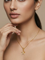 Close-up of a woman wearing a 18k gold plated necklace with a star-shaped pendant on a beige background