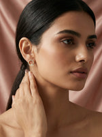 Woman wearing 18k  gold plated earrings against a pink background