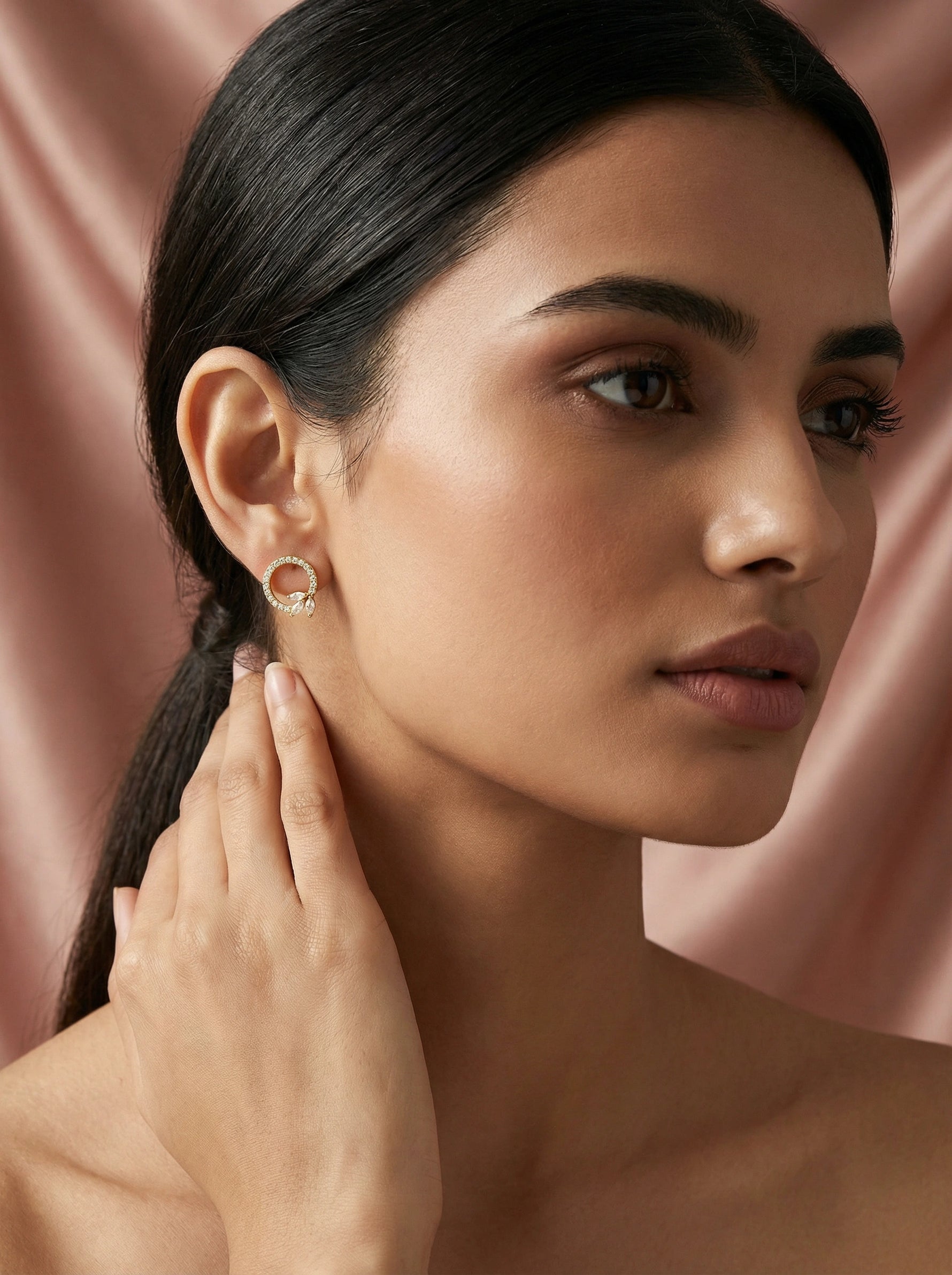 Woman wearing 18k  gold plated earrings against a pink background