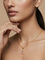 Close-up of a woman wearing a 18k gold plated necklace with a diamond pendant against a beige background