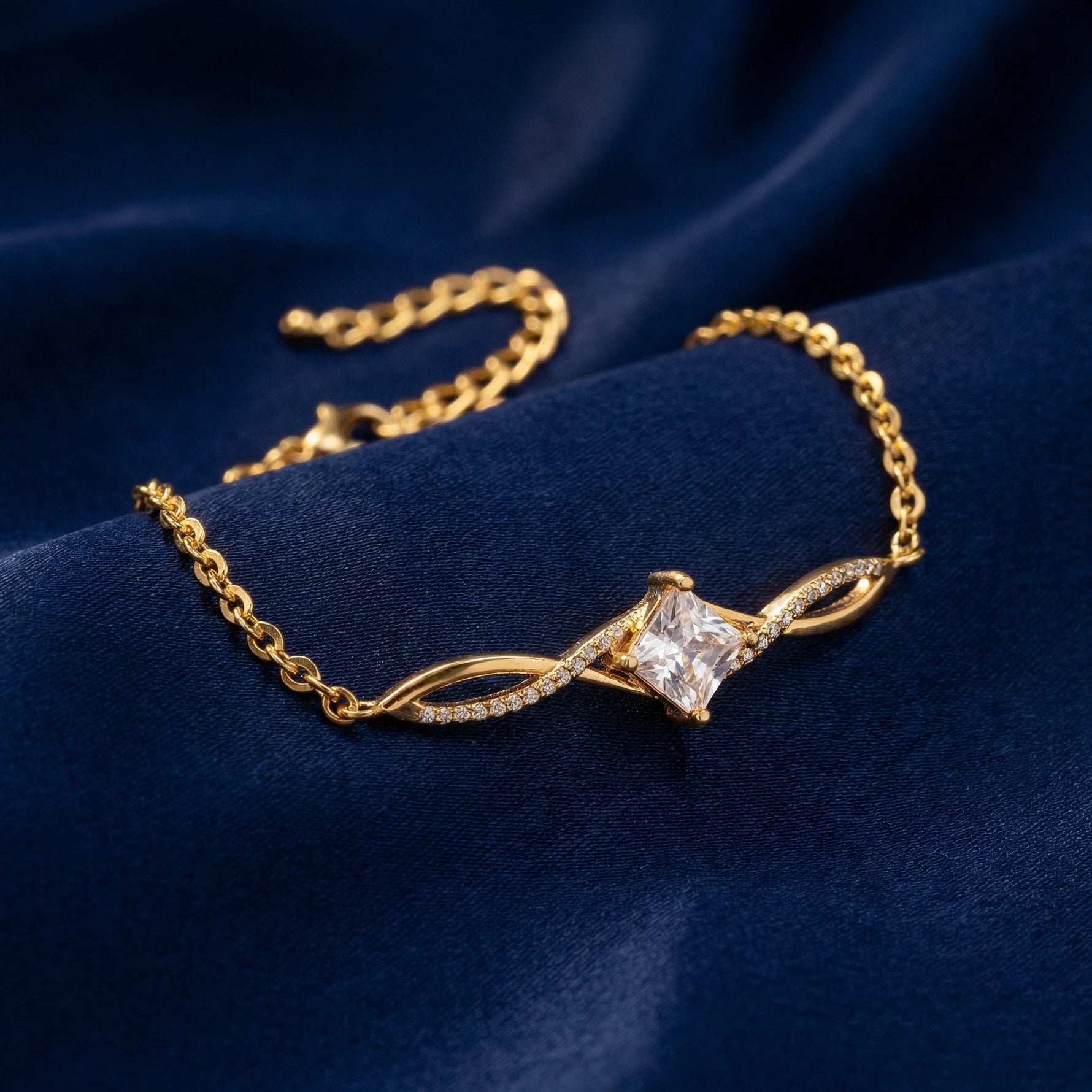 18k Gold plated bracelet with a diamond on a blue fabric background