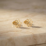 18k Gold plated flower-shaped earrings with diamonds on a beige marble surface